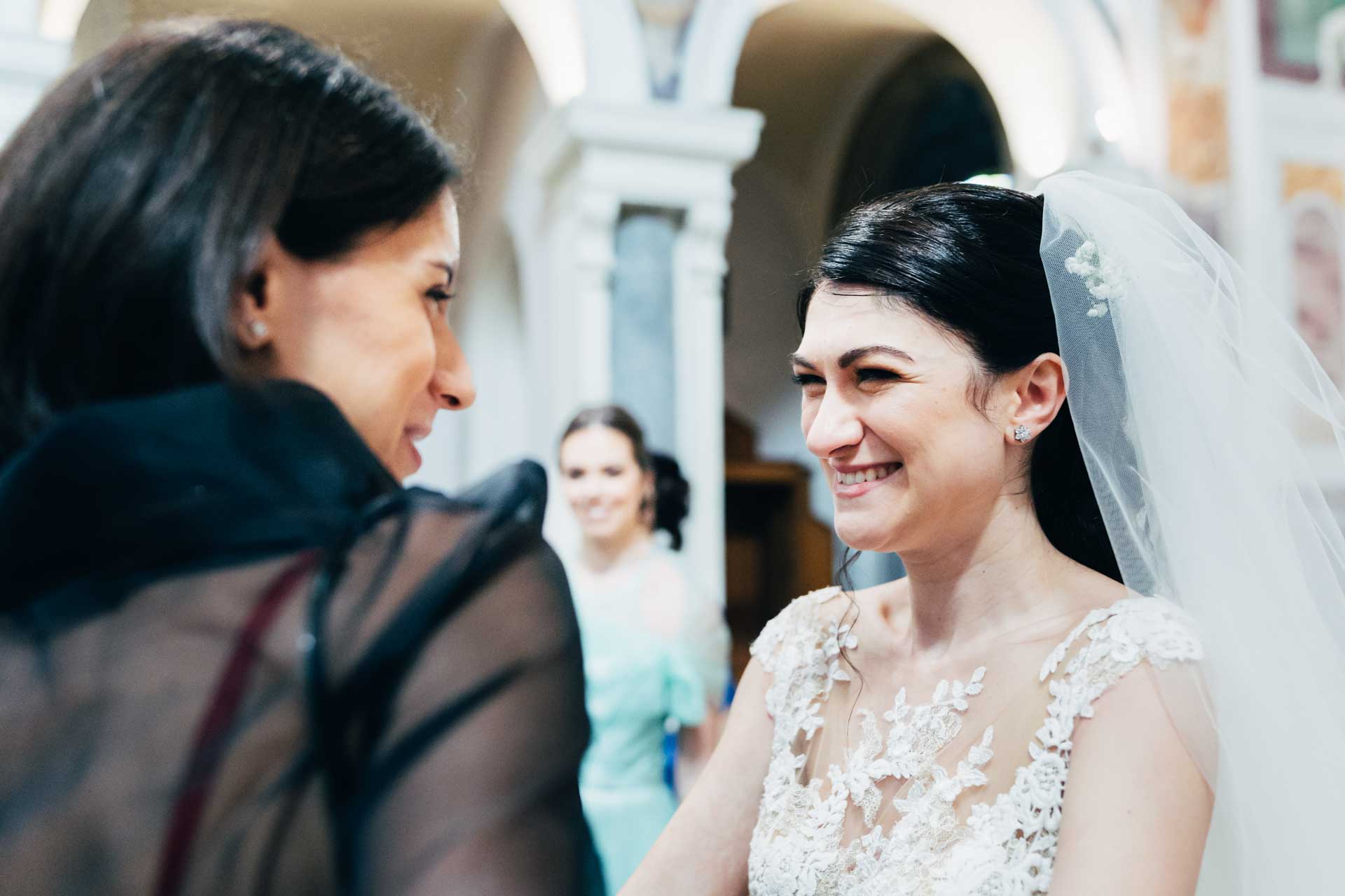 La sposa sorride ad un'invitata nella chiesa di Santa Prisca alla fine del matrimonio