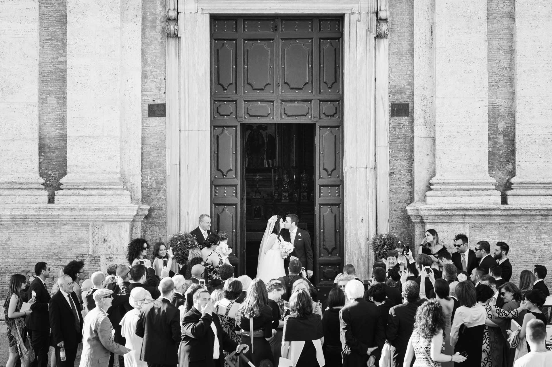 Bacio degli sposi all'uscita della chiesa di Santa Maria di Loreto a Roma durante un matrimonio