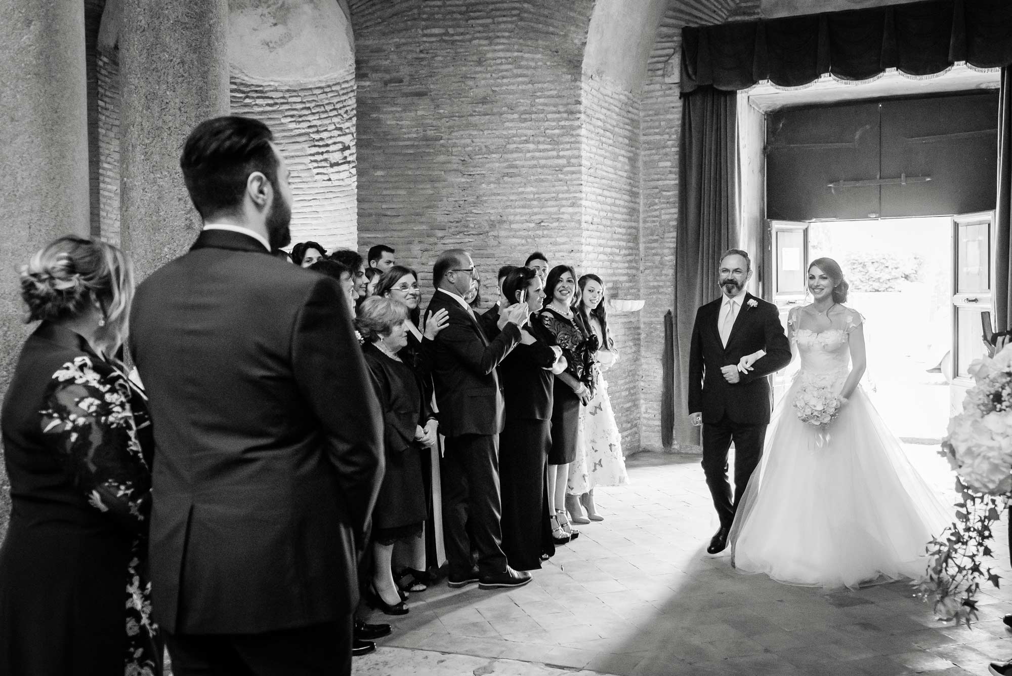 La sposa guarda lo sposo mentre entra con il padre per la cerimonia del Matrimonio nel Mausoleo di Santa Costanza a Roma